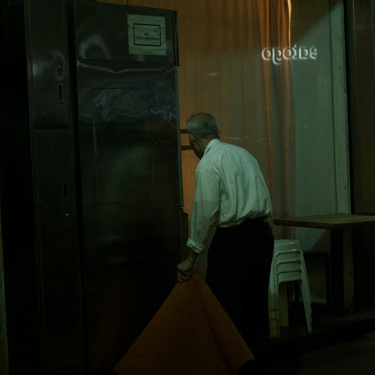 A man is standing near a large refrigerator.