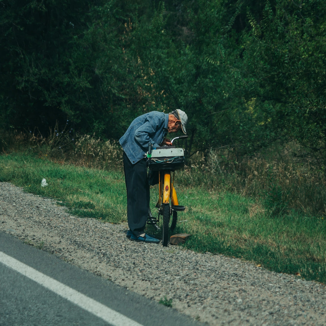A man looks at something beside his bicycle.