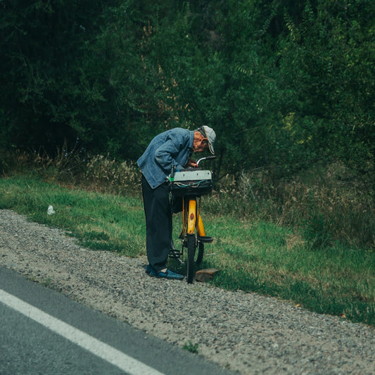 A man looks at something beside his bicycle.