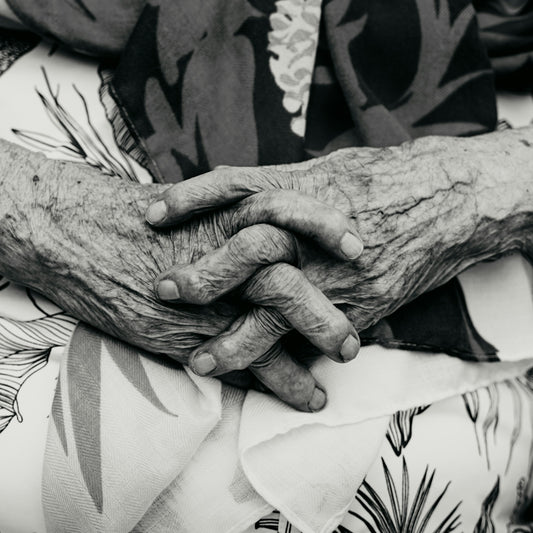 Close-up of elderly hands clasped together.