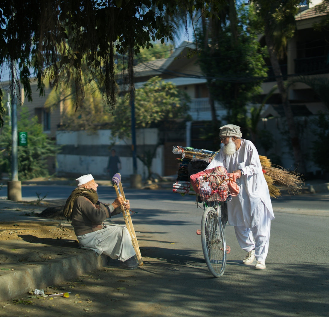 Two men with bicycles on a sunny street.