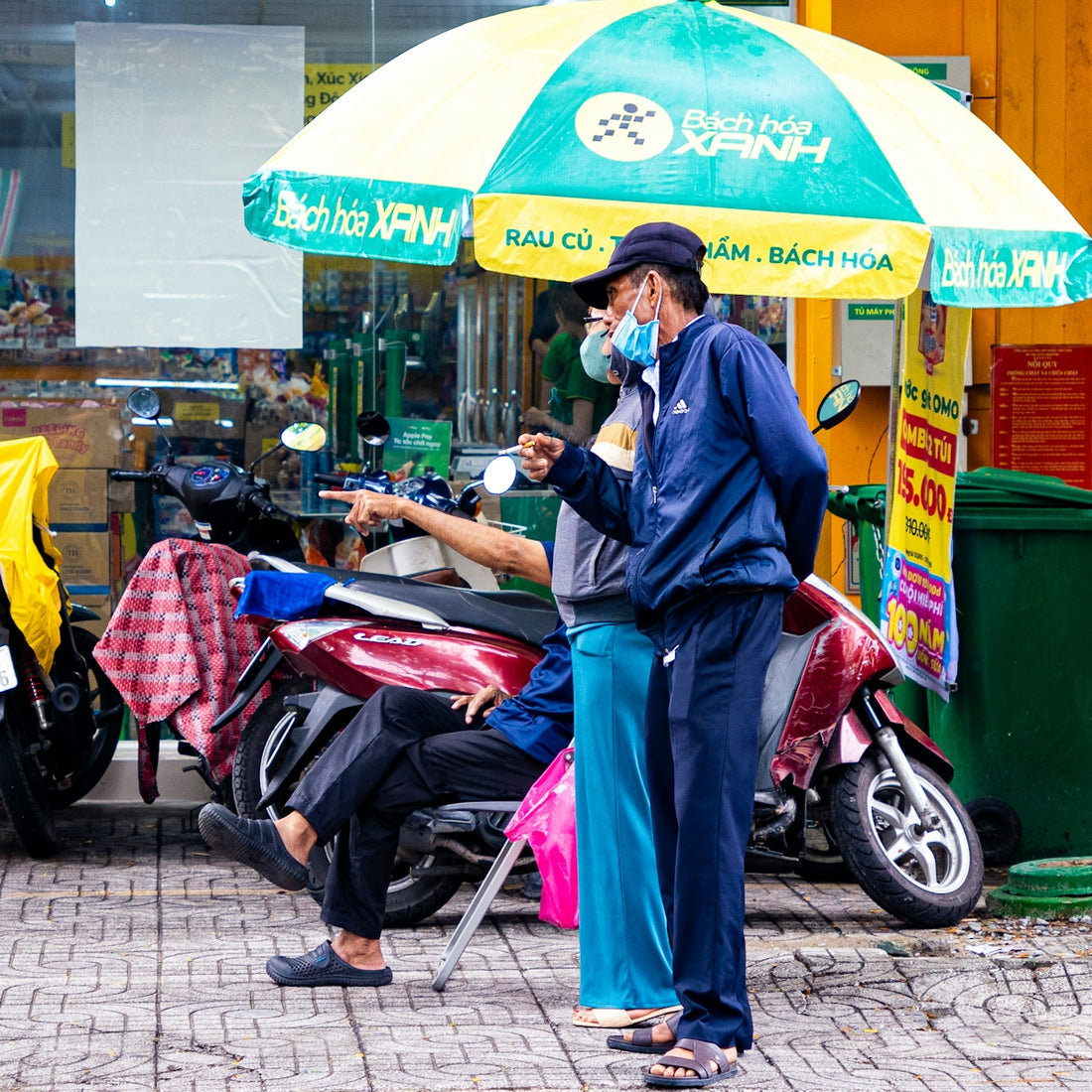 Two men in masks stand near a scooter.