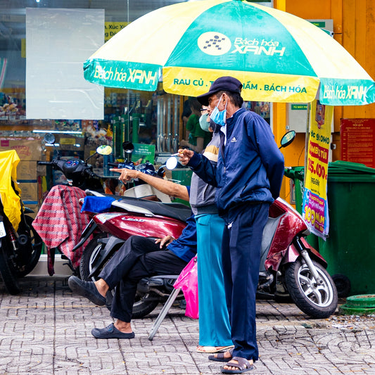 Two men in masks stand near a scooter.