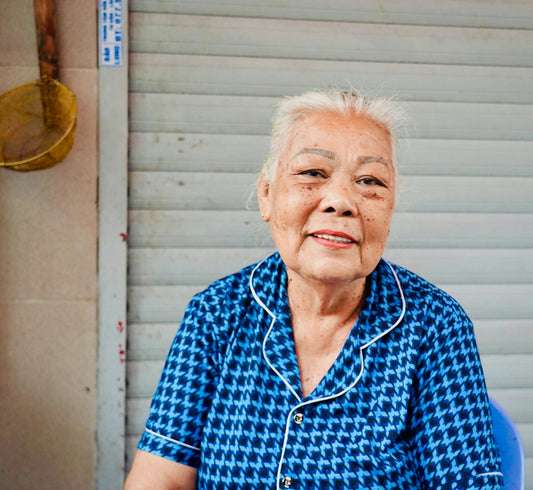 Elderly woman with white hair in blue patterned shirt.